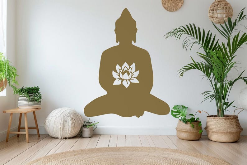 Puede incluir: Una gran silueta dorada de Buda con un dise&ntilde;o de flor de loto blanca est&aacute; fijada a una pared blanca. La imagen es de una habitaci&oacute;n con plantas en cestas y macetas tejidas, un peque&ntilde;o taburete de madera y una alfombra redonda tejida.