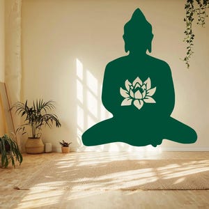 Puede incluir: Silueta verde de Buda con un dise&ntilde;o de flor de loto blanca sobre una pared crema. La habitaci&oacute;n tiene una est&eacute;tica natural y minimalista, con plantas y una alfombra tejida. La luz del sol entra por una ventana.