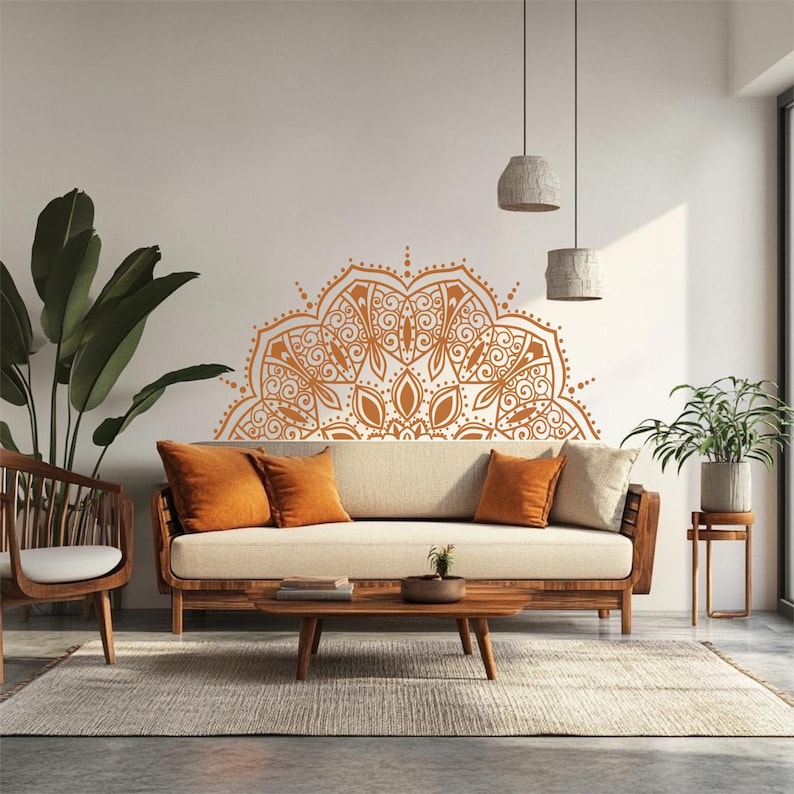 May include: A living room scene featuring a wooden sofa with orange throw pillows and a beige cushion. A large, orange mandala design adorns the wall above the sofa. The room includes a wooden chair, a coffee table, and a rug.