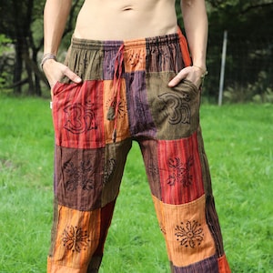 Könnte beinhalten: Patchwork-Hose in Braun-, Orange- und Rottönen. Die Hose hat einen Kordelzugbund und ist mit floralen und geometrischen Mustern verziert.