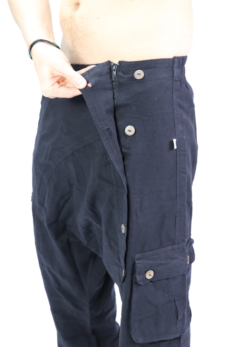 May include: Black cargo pants with a button fly and multiple pockets. The pants are open at the waist and the zipper is visible.
