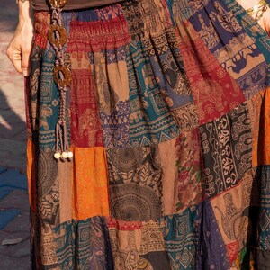 Puede incluir: Una falda larga de retazos multicolores con un cintur&oacute;n marr&oacute;n adornado con grandes cuentas redondas de madera. La falda tiene una variedad de patrones, incluyendo elefantes, paisley y dise&ntilde;os geom&eacute;tricos.