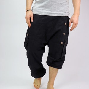 May include: Black cotton pants with a loose, baggy fit and multiple buttons down the side. The pants have a cargo pocket on each leg.