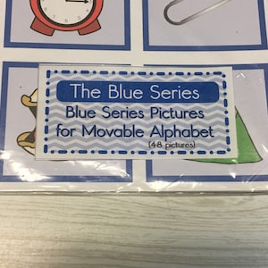 May include: A blue and white card with the text "The Blue Series Blue Series Pictures for Movable Alphabet (48 pictures)"