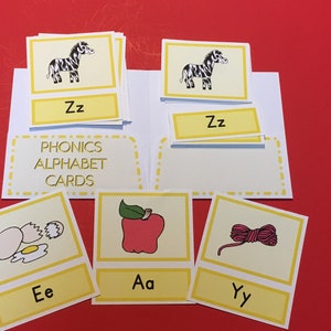May include: A set of phonics alphabet cards with illustrations and letter sounds. The cards feature a zebra, an apple, an egg, and a ball of yarn.