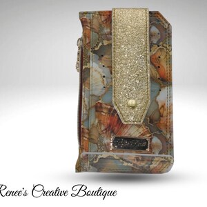 May include: A multi-colored wallet with a gold glitter flap and a small metal nameplate. The wallet features a pattern of orange, brown, and blue swirls. The zipper is visible on the side. The text "Renee's Creative Boutique" is at the bottom.