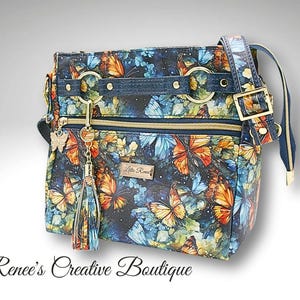 Crossbody met aquarelvlinders, binnen- en buitenzakken met ritssluiting, steekzakken aan de binnenkant, ritssluiting aan de bovenkant. Bijpassende portemonnee beschikbaar