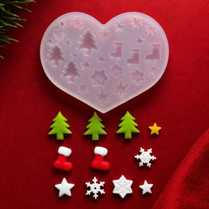 May include: A heart-shaped silicone mold with Christmas-themed shapes, including trees, stars, snowflakes, and stockings. Also, several green Christmas trees, red stockings, white stars, and snowflakes are displayed on a red background.