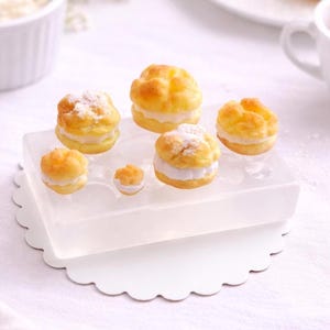 Pode incluir: Um conjunto de três canecas de cerâmica com acabamento fosco e salpicado. As canecas são em tons de creme, cinza claro e cinza escuro. Cada caneca tem um design simples e minimalista e uma alça arredondada.