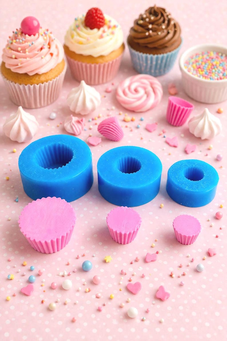 May include: An assortment of cupcakes with colorful frosting and sprinkles, alongside blue silicone molds and pink cupcake liners. Decorative meringues and sprinkles are scattered on a pink polka dot surface.