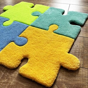 May include: A set of four interlocking puzzle piece rugs in bright colours. The pieces are lime green, teal, light blue, and yellow. Each piece features a thick, tufted texture with rounded edges and distinct tabs and blanks that fit together.