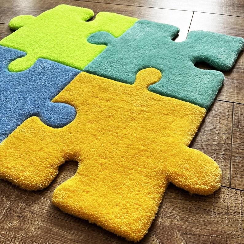 May include: A set of four interlocking puzzle piece rugs in bright colours. The pieces are lime green, teal, light blue, and yellow. Each piece features a thick, tufted texture with rounded edges and distinct tabs and blanks that fit together.