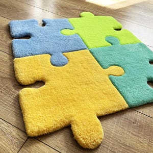May include: A tufted rug composed of four interlocking puzzle piece shapes in bright colours. The individual pieces are coloured in light blue, lime green, yellow, and teal. Each piece features the characteristic tabs and blanks of a puzzle.