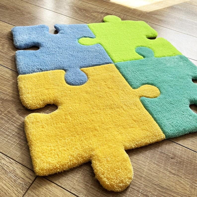 May include: A tufted rug composed of four interlocking puzzle piece shapes in bright colours. The individual pieces are coloured in light blue, lime green, yellow, and teal. Each piece features the characteristic tabs and blanks of a puzzle.