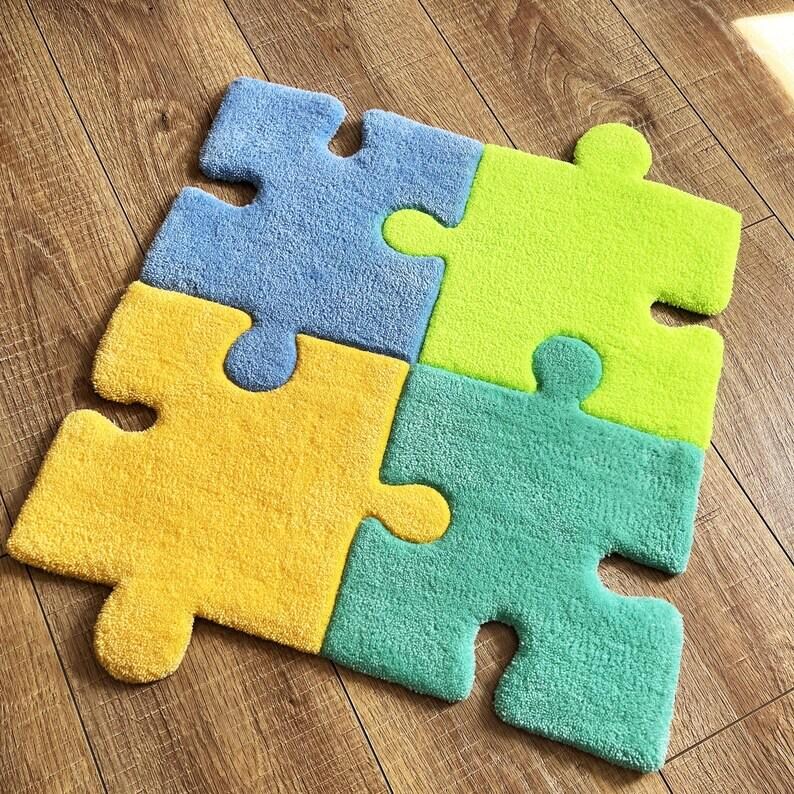 May include: A four-piece puzzle rug featuring interlocking segments in light blue, lime green, yellow, and teal. Each piece has a soft, textured pile surface, and the assembled shape forms a square with rounded edges and distinct puzzle tabs.