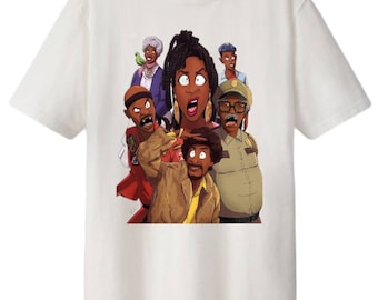 May include: White t-shirt with a colorful cartoon illustration of a group of people. The characters are all Black and have exaggerated features. The characters are wearing various outfits, including a police uniform, a red jacket, and a brown coat.