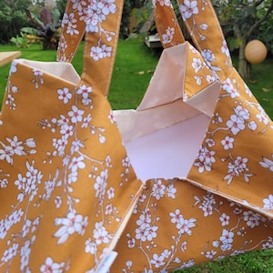Taart-, quiche-, tortilla-, taarttasje van mosterdkleurig Oeko Tex-katoen met bloemmotieven. Milia-Loka Biarritz.