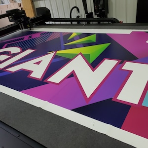 May include: A large banner with the word "GIANT" printed in white letters on a colorful background of pink, purple, blue, green, and black geometric shapes.