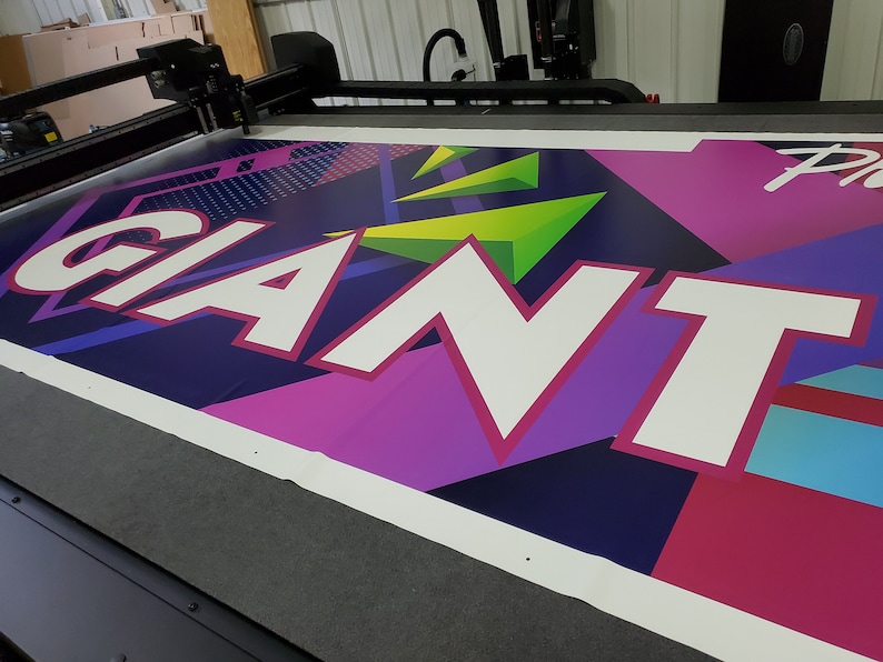 May include: A large banner with the word "GIANT" printed in white letters on a colorful background of pink, purple, blue, green, and black geometric shapes.