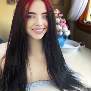 May include: A long, black wig with a vibrant red top section. The wig is styled with long, straight hair and is displayed on a mannequin head. The wig's color transition is a striking contrast, offering a bold and fashionable look.