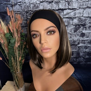 May include: A mannequin head with shoulder-length brown hair with blonde highlights, wearing a black headband. The mannequin is wearing makeup and has a neutral expression.
