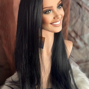 May include: A long, straight black wig with a lace front. The wig is styled with a center part and falls to the shoulders. The wig is on a mannequin head.