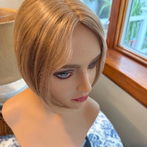 May include: A blonde wig with a short, blunt bob hairstyle. The wig is styled with a side part and has a natural-looking finish.