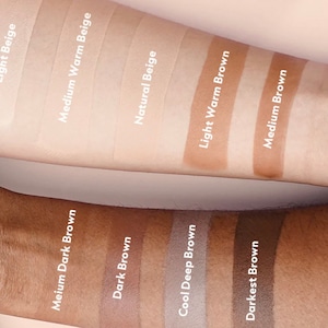K&ouml;nnte beinhalten: Nahaufnahme von zehn Foundation-Farbt&ouml;nen auf einem Arm. Die Farbt&ouml;ne reichen von hellem Beige bis zu dunkelster Braun. Die Farbt&ouml;ne sind mit ihren Namen beschriftet: Hellbeige, Mittelwarm Beige, Naturbeige, Hellwarm Braun, Mittelbraun, Mittel Dunkelbraun, Dunkelbraun, K&uuml;hles Tiefbraun und Dunkelstes Braun.