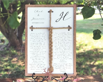 May include: A wooden sign with a white background and a brown frame. The sign features a rope knot in the shape of a cross with the text "Chad & Jessica" and "September 24, 2024" at the top. The text "H" is written in cursive at the top right corner of the sign. The sign also includes a passage of text about love and marriage.