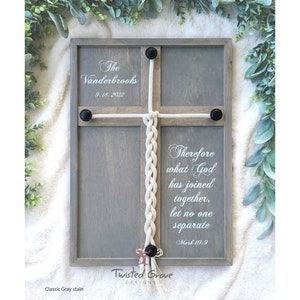 May include: A wooden sign with a gray stain and a white rope tied in a knot. The sign has the text "The Vanderbrooks 9.18.2022" and "Therefore what God has joined together, let no one separate Mark 10:9". The sign also has the text "Twisted Grove Designs" at the bottom.