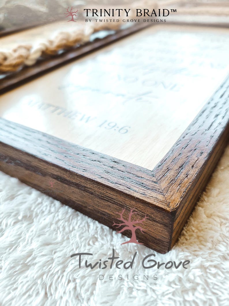 May include: A wooden framed sign with a white background and the text "Let the little things that make you smile be your reminder that life is good" and "Matthew 19:6". The sign is on a white fuzzy surface. The sign is made by Twisted Grove Designs.