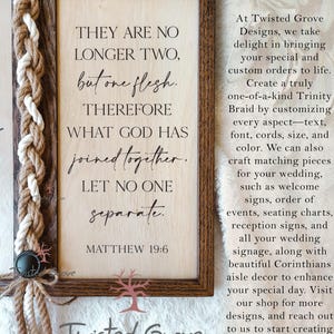May include: A wooden sign with a brown frame and a white background. The sign features a quote from the Bible, Matthew 19:6, "They are no longer two, but one flesh. Therefore what God has joined together, let no one separate." The sign is decorated with a braided rope.