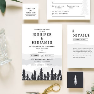May include: A wedding invitation suite with a woodland theme. The main invitation features a watercolor background with a silhouette of a forest. The RSVP card has a simple design with a pine tree graphic. The details card has a mountain range graphic and text that says "Details".