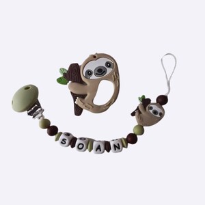 Könnte beinhalten: Ein brauner und grüner Silikon-Beißring mit einem Faultier-Design. Der Beißring ist an einer braunen und grünen Perlenkette befestigt, auf der der Name "SOAN" in weißen Perlen geschrieben steht.