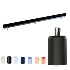 Könnte beinhalten: Schwarze rechteckige Deckenleuchte mit drei Befestigungspunkten. Eine schwarze zylindrische Lampenfassung wird neben einer Vielzahl farbiger Lampenfassungsabdeckungen gezeigt: transparent, schwarz, weiß, marineblau, silber, gold und kupfer.