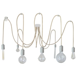 Può includere: Un apparecchio di illuminazione moderno con sei lampadine bianche avvolte da un cavo che pendono da un soffitto. Le lampadine sono disposte in modo casuale e hanno forme e dimensioni diverse.