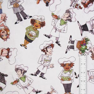 May include: A white fabric featuring a repeating cartoon pattern of chefs in various poses, wearing white hats and uniforms. A clear plastic ruler is positioned along the bottom and right edges, showing measurements in inches for scale.