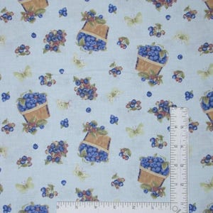 May include: A light blue fabric featuring a repeating pattern of brown baskets filled with dark blue blueberries, scattered individual berries, and pale yellow butterflies. An L-shaped white ruler shows a scale of 5 inches by 4 inches.