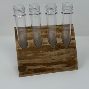 May include: Four clear plastic test tubes with screw-on lids are displayed in a wooden stand. The stand is made of light brown wood with a natural grain pattern.