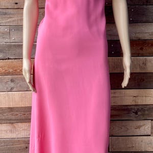 May include: A pink maxi dress with a floral lace bodice and short sleeves. The dress is made of a lightweight fabric and has a simple, elegant design.
