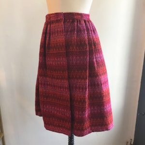 May include: A red, pink, and black patterned skirt with a pleated design. The skirt is knee-length and has a straight silhouette.