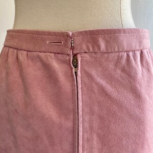 May include: A dusty rose-colored suede skirt with a zipper closure in the back.