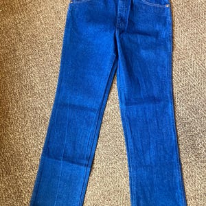 May include: Bright blue denim jeans with a classic five-pocket design. The jeans have a button and zipper closure, belt loops, and a straight leg cut. The fabric appears to be a medium-weight denim.