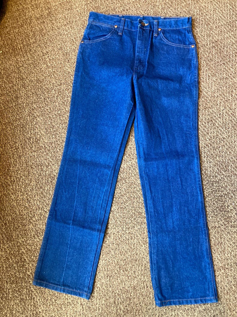 May include: Bright blue denim jeans with a classic five-pocket design. The jeans have a button and zipper closure, belt loops, and a straight leg cut. The fabric appears to be a medium-weight denim.