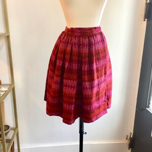 May include: A red and pink patterned skirt with a high waist and a flared silhouette.