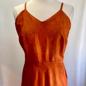 May include: A burnt orange sleeveless dress with a V-neckline and a flowy skirt.