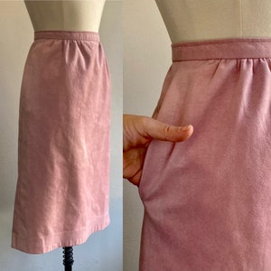 May include: A dusty rose suede skirt with a straight, fitted silhouette. The skirt has a simple design with a waistband and a smooth, textured surface.