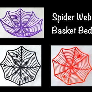 May include: Four spider web shaped baskets, two purple, one black, and one orange. The baskets are made of plastic and feature a spider design. The text "Spider Web Basket Bed" is written in white on a black background.