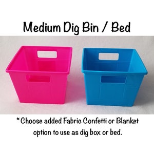 May include: Two plastic storage bins, one pink and one blue, with handles. The text "Medium Dig Bin / Bed" is above the bins. The text "* Choose added Fabric Confetti or Blanket option to use as dig box or bed." is below the bins.