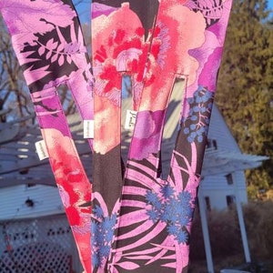 Peut inclure: Trois bandeaux en tissu avec des motifs floraux. Le bandeau de gauche a un motif floral violet et rose, le bandeau du milieu a un motif floral rose et rouge, et le bandeau de droite a un motif floral noir et rose.